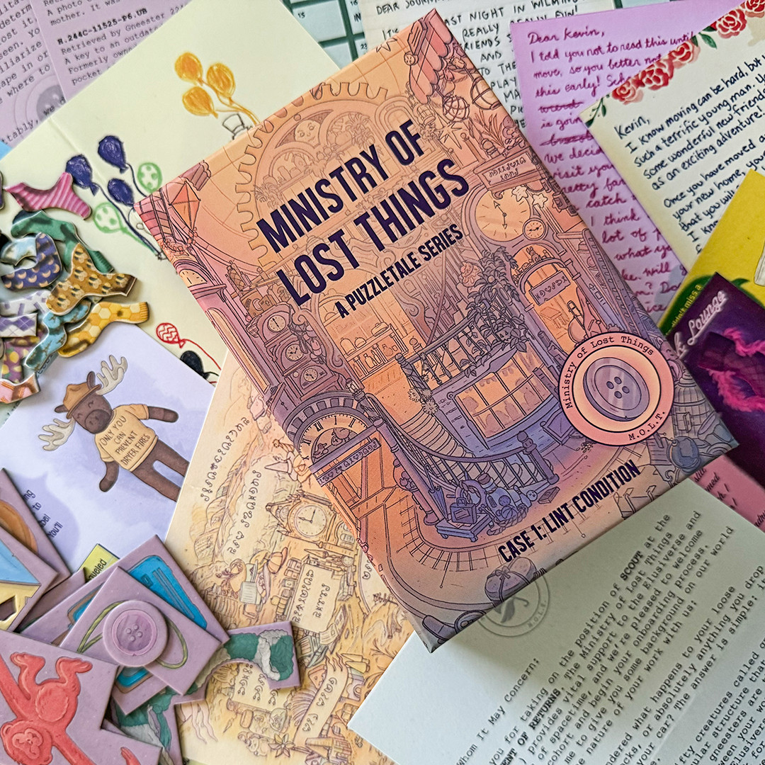 The board game "Ministry of Lost Things" sits amidst colorful letters, stickers, and decorative items, hinting at its Kickstarter origins. The cover's intricate clockwork designs promise a whimsical journey in this narrative puzzle game filled with mystery.